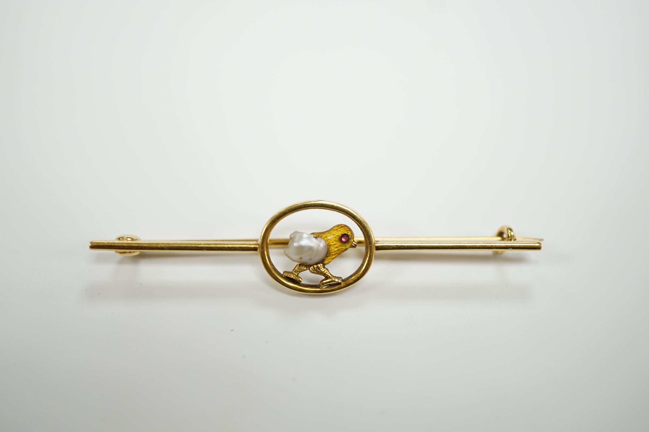 An early 20th century yellow metal, enamel and single stone baroque pearl set bar brooch, modelled as a hatching chick, 50mm, gross weight 3.8 grams.